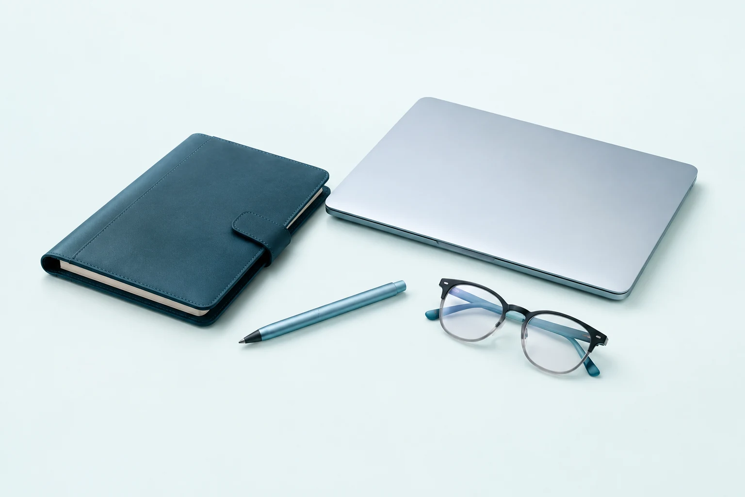 Laptop, folder, pen and glasses arranged as a meeting kit